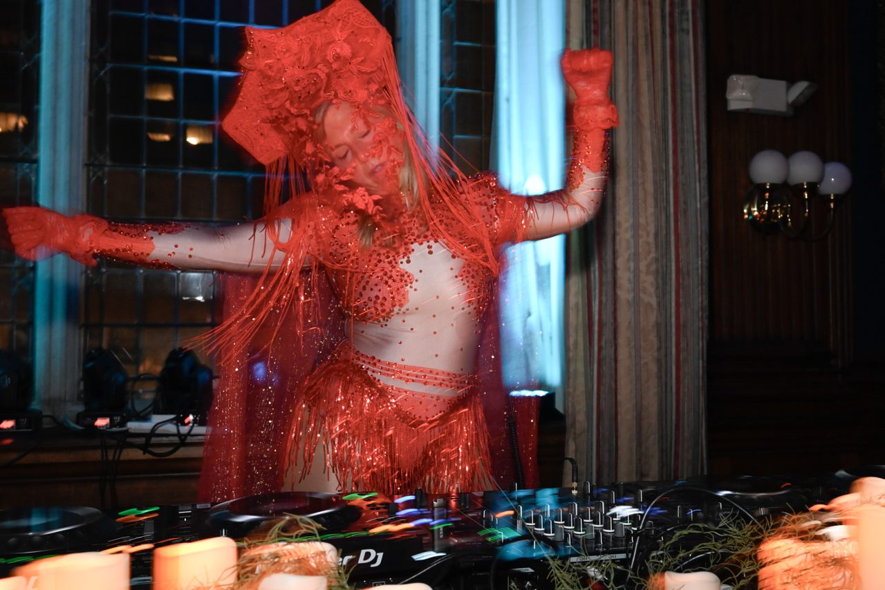 Daniela in character at the Mütter Museum: a red headdress and fringed veil, arms flung wide above the decks
