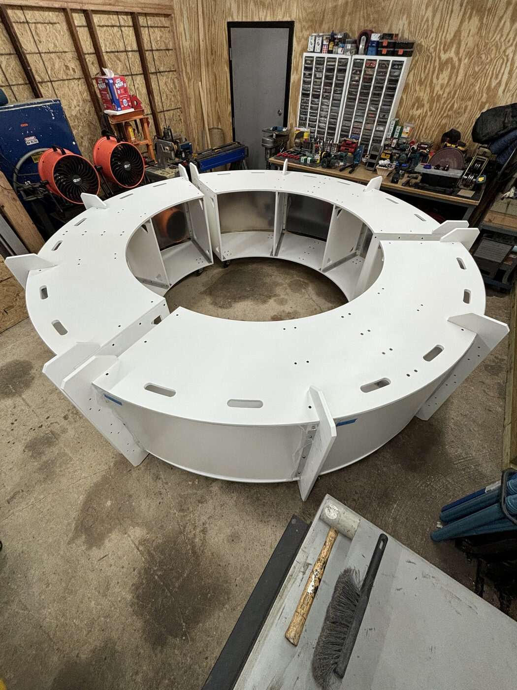 The 360° booth mid-build in the workshop: a white ring of flat-pack sections