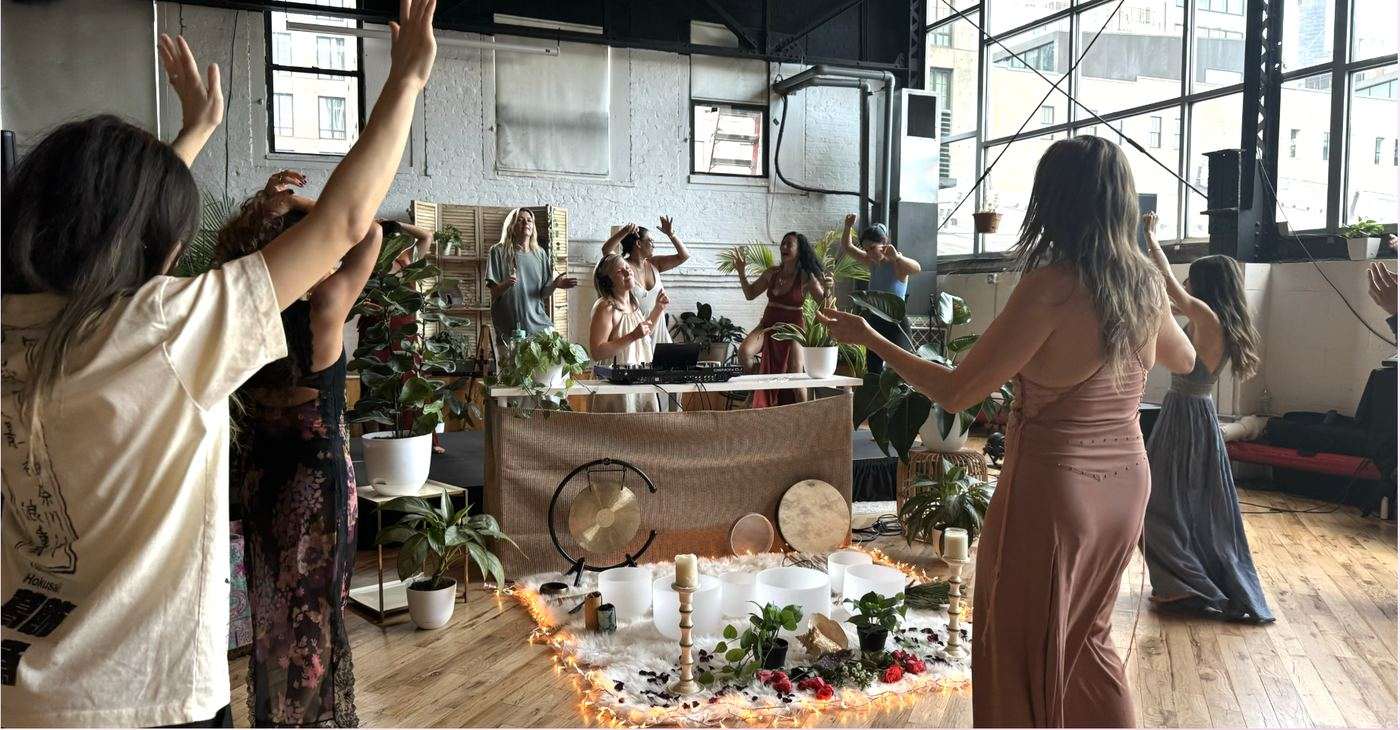 Women dancing with arms raised around an altar at the Goddess Gathering