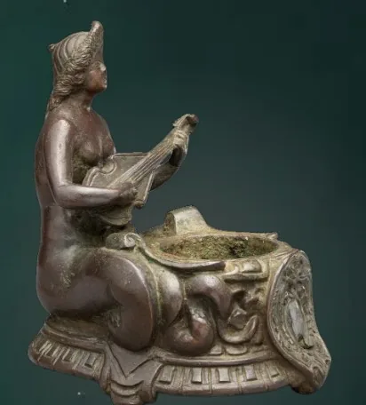 A bronze siren seated with a mirror
