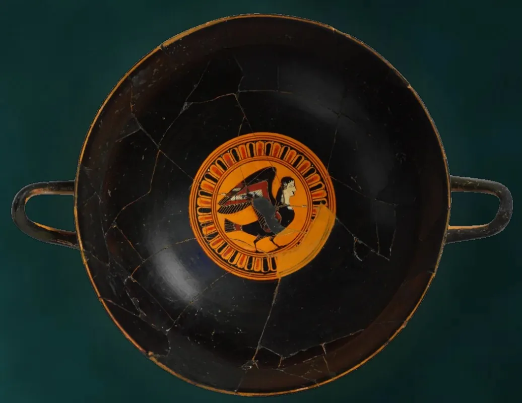 A black drinking cup with a small painted siren medallion